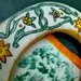 Cornice ovale di ceramica fatta a mano con motivi di arabeschi verde ramina e fiori arancio e giallo