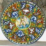 Piatto stile 400 di maiolica con putto centrale e spazi con foglie fiori delfini e mascherone