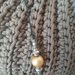 Piccola pochette elegante realizzata con cordino color tortora e impreziosita con  tracollina contenente perle  dorate            
