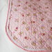 Copertina neonata rosa in cotone trapuntato,rifinita con sbieco rosa e pizzo bianco con angoli arrotondati