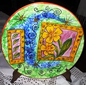 Piatto ceramica decorato a mano con  fiori e foglie racchiuse in 2 cornici su fondo verde e blu mischiato