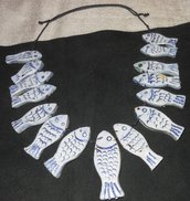 Tanti pesciolini di ceramica incisi per collana simmetrica disposti dal centro in ordine decrescente 