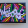 Tavoletta in legno con scritta di benvenuto con sfondo colorato racchiusa in una pergamena