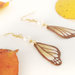 Orecchini pendenti con ali di farfalla dorate in pasta di mais/porcellana fredda modellate e dipinte a mano, componenti in acciaio dorato