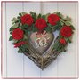 Cuore in vimini tinta naturale decorato con rose rosse, rametti verdi e cuore di lino grezzo con scritta joy