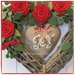 Cuore in vimini tinta naturale decorato con rose rosse, rametti verdi e cuore di lino grezzo con scritta joy