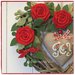 Cuore in vimini tinta naturale decorato con rose rosse, rametti verdi e cuore di lino grezzo con scritta joy