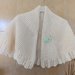 Ampia mantellina -coprispalle realizzata in lana di colore panna  con spilla a forma di fiore che orna e permettere di chiudere lamantellina 