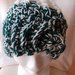 Cappello di lana bicolore panna e verde realizzato a uncinetto a punto a rilievo che forma degli spicchi e con anello sulla fascia frontale