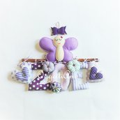 Targa nascita in stoffa decorata con nome, fiorellini, una farfalla e un fiocco sulle tonalità del lilla, viola e verde per annunciare la nascita della piccola Zoe