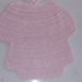 Bavaglino da neonata realizzato a uncinetto con filo di scozia rosa con disegno a forma di vestitino 