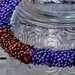 Braciale con fili di perline multicolore cucite a mano su cilindro senza chiusura nei colori viola e bronzo