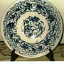 Piatto di maiolica dipinto a mano con varie sfumature di blu con motivo centrale e sulla falda di uccellino lumaca fiore e foglie