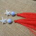 Orecchini stella marina con nappina di seta rossa..