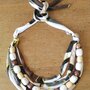 Collana multifilo girocollo regolabile realizzata con 4 fili di fettuccia di cotone fantasia e filo di perle di legno marroni rivestite in carta