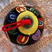 Pallina di Natale di ceramica dipinta a mano su un fondo nero tanti anelli multicolore per addobbare l'albero