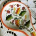 cucchiao poggia mestoli di ceramica dipinto a mano con fiori foglie e gancett nei colori verde chiaro e scuro, giallo arancio e rosso profilato di arancio