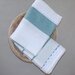 Coppia asciughini da cucina di colore panna  e decorato  con delicato merletto a ondine posto in un cestino d ivimini 