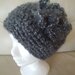 Cappello realizzato a uncinetto con filato  in lana e alpaca di colore grigio puntinato panna con grazioso fiore laterale