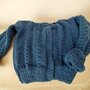 Giacchino da bimbo realizzato a ferri con filato di lana color blu acciaio. Impreziosito da treccine  sul davanti, sul dietro e sulle maniche