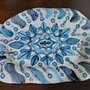 Vassoio di ceramica manufatto forma ovale falda irregolare dipinta a mano con rosone centrale in vari  toni blu