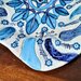 Vassoio di ceramica manufatto forma ovale falda irregolare dipinta a mano con rosone centrale in vari  toni blu