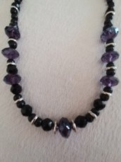 Elegante collana  realizzata a mano con perle nere tonde e sfaccettate alternate da pietre più grandi sfaccettate  di colore viola  con distanziatori formati da tondini di metallo e perle di color argento. 