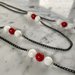 Collana medio lunga con catenella nera in alluminio e inserti di perle di pietra dura bianche e rosse