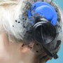 Accessorio per i capelli. Un fermaglio per una ragazza. A forma di cappello, con velo e piume.