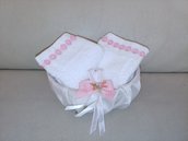 Elegante cestino foderato con raso bianco decorato con delicato fiocco rosa contenente una coppia di lavette decorate con pizzo macramè