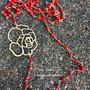 Collana lunga a rosario con cristalli rossi e fiore in zama 