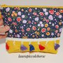 Pochette fantasia fiori e gialla con decorazione con piccole nappine e zip