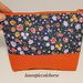 Pochette fantasia fiori e arancione con decorazione con piccole nappine e zip