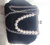 Pochette in cordino nero con chiusura clic clac, con tracolla a catenella e manico in perle