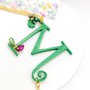 Collana lunga con catenina dorata e lettera M verde pendente, decorata con perle di vetro