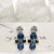 Orecchini pendenti a perno con strass bianchi e blu petrolio, collezione LUCE