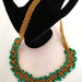 Collana realizzata a mano ad uncinetto con filato gioiello color oro e mezzi cristalli verdi