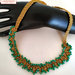 Collana realizzata a mano ad uncinetto con filato gioiello color oro e mezzi cristalli verdi