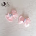 due fermacapelli a pinza con fiocco rosa decorati con dolcetti ciambella e marshmallow
