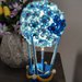 Splendida mongolfiera azzurra che si illumina, con fiorellini e perline