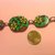 Bracciale in fimo con perle a forma di ovale su base verde con fiori e rose nei toni del giallo e viola