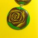 Ciondolo in fimo su base verde con fiori e rose nei toni del giallo e viola