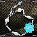 Bracciale con perle e connettore fiore smaltato azzurro con strass centrale.