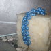 Braccialetto con perle shell inserite nel tubolare a rete azzurra.