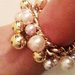 Bracciale catena d'oro e perle di varie dimensioni e colori.