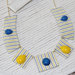 Collana a segmenti, in stoffa gialla e azzurra a righe con pietre cabochon in plastica