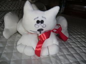 Pupazzo gatto in panno imbottito color bianco con fiocchi rossi. Ideale per abbellire i letti dei bambini