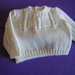 Completo bianco composto da  pantaloncino,  maglioncino e scarpine realizzato ai ferri in pura lana vergine