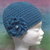 Cappello in lana color petrolio con fiore e perla