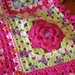 Copertina a mattonelle multicolore con rosa in rilievo realizzata all'uncinetto